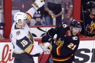 Vegas Golden Knights' Pavel Dorofeyev, left, battles with Calgary Flames' Kevin Rooney, right, during the first period of an NHL hockey game in Calgary, Alberta, Thursday, March 14, 2024. (Larry MacDougal/The Canadian Press via AP)