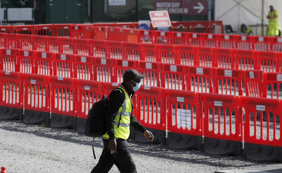 A staff member walks past empty lanes of a Covid-19 drive thru testing facility at Twickenham stadium in London, Thursday, Sept. 17, 2020. Britain has imposed tougher restrictions on people and businesses in parts of northeastern England on Thursday as the nation attempts to stem the spread of COVID-19, although some testing facilities remain under-utilised. (AP Photo/Frank Augstein)