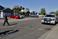 A Phoenix police officer lays out crime scene tape outside the scene of a deadly shooting early Monday, March 30, 2020, in Phoenix. Phoenix police say one of their commanders was killed and two other officers were wounded as they responded to a domestic dispute. Authorities say Cmdr. Greg Carnicle and officers were called to a home in the northern part of Phoenix Sunday night over a roommate dispute when the suspect refused to cooperate and shot them. The suspect was not identified and was pronounced dead at the scene. (AP Photo/Matt York)