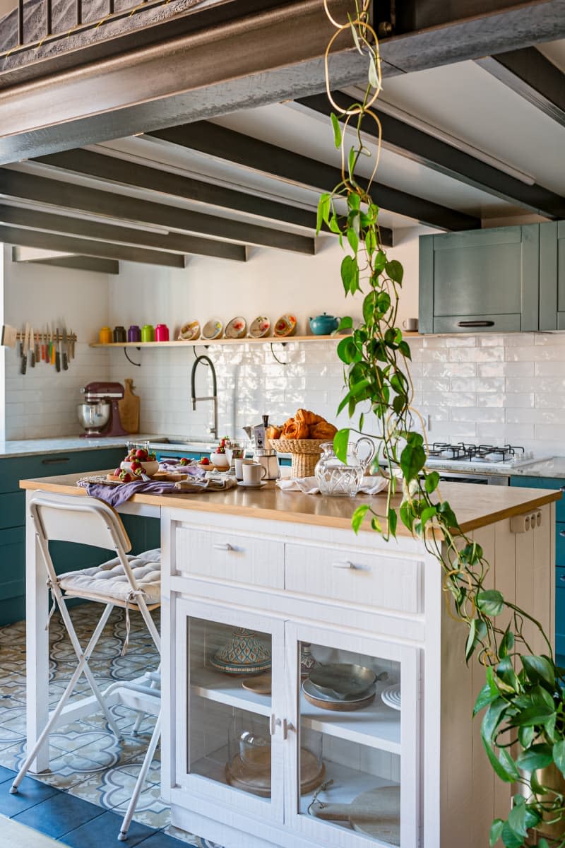 White kitchen island with storage and wooden top.