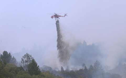 A helicopter drops water on a wildfire in Sonoma, California - Credit: AP