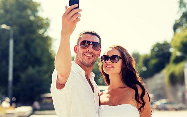 A sunglasses-loving couple take a selfie in the sun - Credit: Lev Dolgachov / Alamy Stock Photo