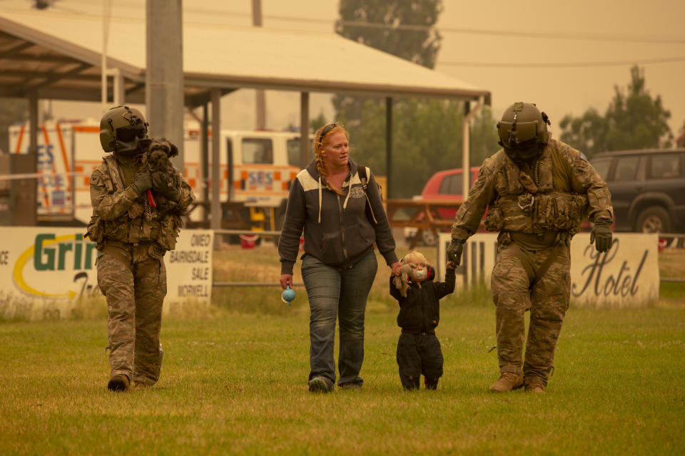 Two Australian Army Soldiers help people evacuate at Omeo showgrounds.