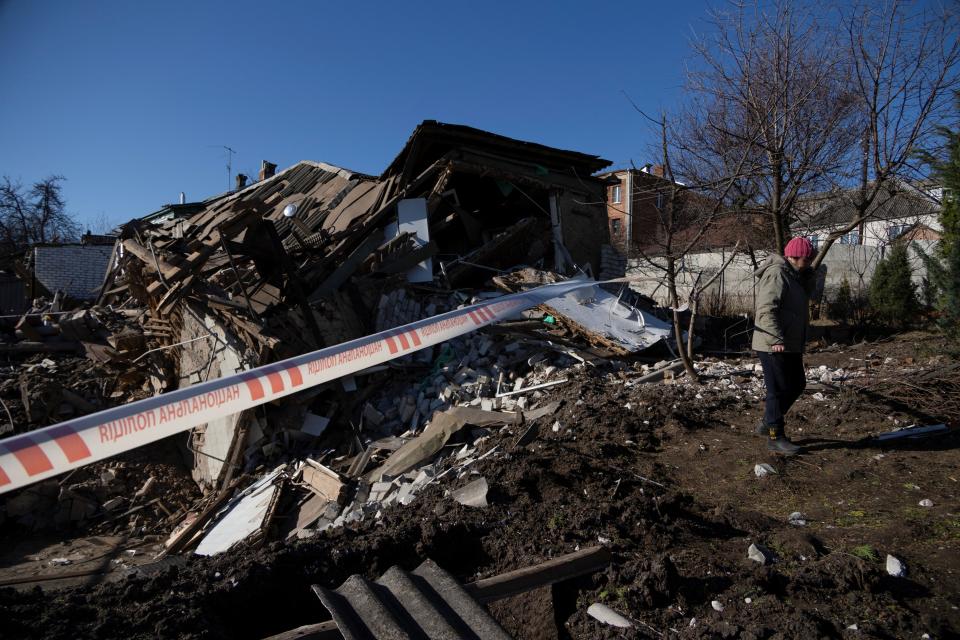 A woman stands next to a residential house destroyed by a Russian missile strike, amid Russia's attack of Ukraine, in Kharkiv (REUTERS)