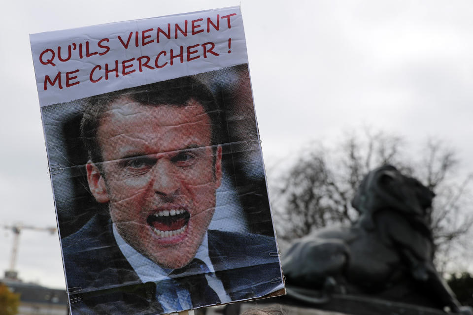 A placard depicting a portrait of French President Macron and reading "Let them come to take me" is displayed during their 56th round in Paris, Saturday, Dec. 7, 2019. A few thousand yellow vest protesters marched Saturday from the Finance Ministry building on the Seine River through southeast Paris, pushing their year-old demands for economic justice and adding the retirement reform to their list of grievances. (AP Photo/Francois Mori)