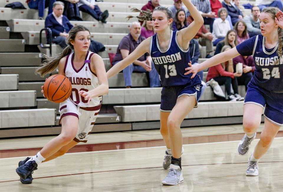 Stow guard Alaina Ray drives past Hudson's Paige Sutton (13) and Emma Hileman (24) Wednesday, Dec. 7, 2022.
