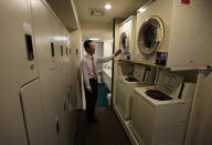 Manager Akiyoshi Kaneko stands by coin-operated washing machines at the Capsule & Sauna Century Shibuya in Tokyo. (AP Photo/Shizuo Kambayashi)