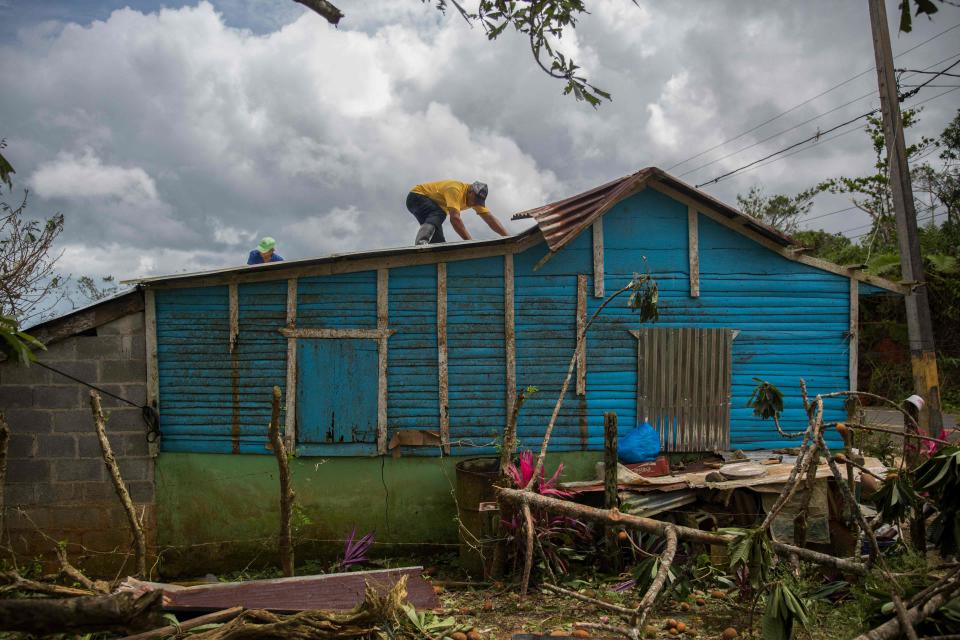 A man repairs the roof of a house after the passage of Hurricane Fiona. Roof repair can be one of the costliest emergency expenses.