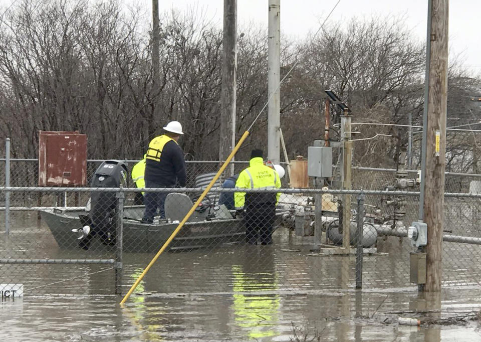 In this Wednesday, March 20, 2019 photo provided by the Missouri State Highway Patrol shows Water Patrol Troopers assisting utility company employees in shutting off natural gas lines in flood waters at Craig, Mo. In northwest Missouri, a levee breached Tuesday, unleashed a torrent that overwhelmed a temporary berm that was built up with excavators and sandbags to protect the small town of Craig, where the 220 residents have been ordered to evacuate. "They've got water running down Main Street," said Tom Bullock, emergency management director of Holt County, where Craig is located. (Missouri State Highway Patrol, via AP)