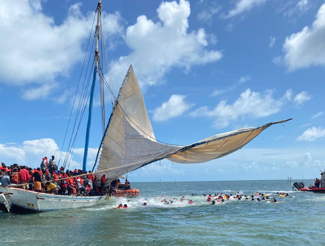 Several people from a Haitian migrant boat jump in the water off the Ocean Reef community in north Key Largo Saturday, Aug. 6, 2022. They were part of a large migrant group of between 100 and 200 people who arrived in an overloaded sailboat.