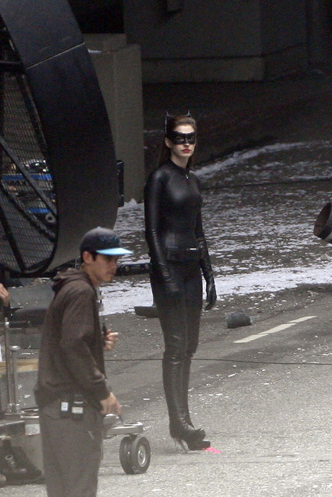 <p>Hathaway cools her very-tall Catwoman heels on the set of the 2012 sequel. <i>(Photo: PhamousFotos / Splash News)</i></p>