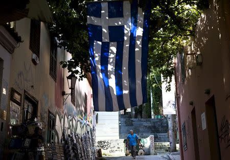 A souvenir shop owner cleans the sidewalk at the Plaka district under the Acropolis hill in Athens, Greece July 23, 2015. REUTERS/Ronen Zvulun