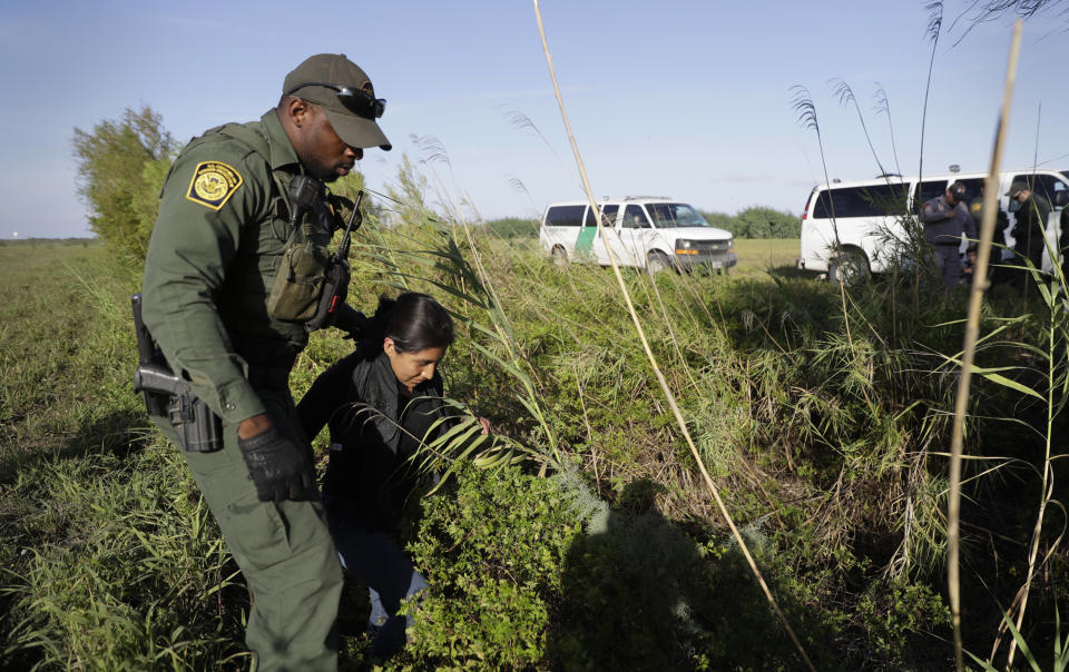 FILE - In this Aug. 11, 2017 file photo a U.S. Customs and Border Patrol agent escorts an immigrant suspected of crossing into the United States illegally along the Rio Grande near Granjeno, Texas. The number of unaccompanied children encountered on the U.S. border with Mexico in April 2021 eased from an all-time high a month earlier, while more adults are coming without families. Authorities encountered nearly 17,200 children traveling alone, down 9% from March but still far above the previous high in May 2019. (AP Photo/Eric Gay, File)