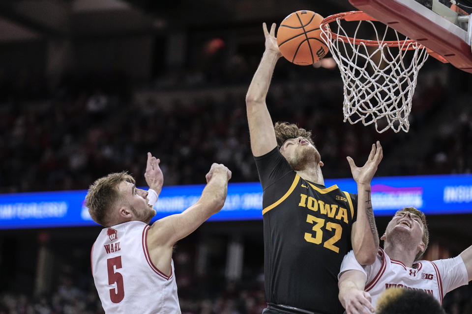 Iowa's Owen Freeman (32) grabs an offensive rebound against Wisconsin's Tyler Wahl (5) and Steven Crowl during the first half of an NCAA college basketball game Tuesday, Jan. 2, 2024, in Madison, Wis. (AP Photo/Andy Manis)
