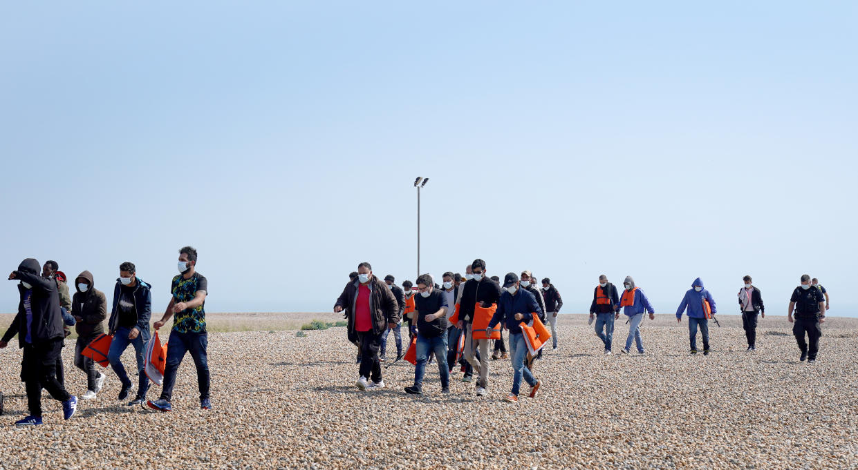 A group of people thought to be migrants are escorted from the beach in Dungeness, Kent, by Border Force officers following a small boat incident in the Channel. Picture date: Tuesday July 20, 2021.