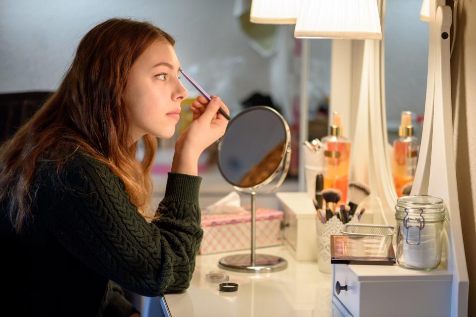 A person applies makup in front of a mirror.