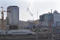 A train drives into Harbin railway station as smoke is seen from the chimney of a heating station in Harbin