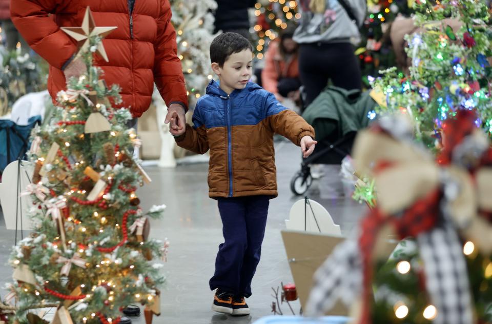Caleb Kinikini explores the 53rd annual Festival of Trees to benefit Intermountain Primary Children’s Hospital patients, with his grandfather at the Mountain America Expo Center in Sandy on Monday, Nov. 27, 2023.