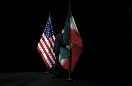 A staff member removes the Iranian flag from the stage after a group picture with foreign ministers and representatives during the Iran nuclear talks at the Vienna International Center in Vienna