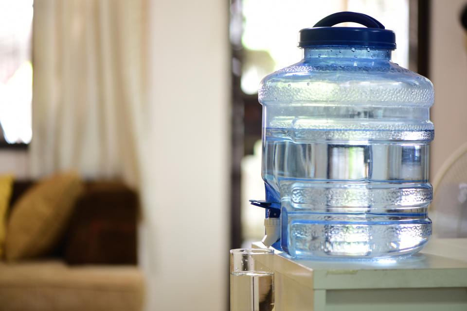 Large water dispenser on a countertop in a room with a couch in the background