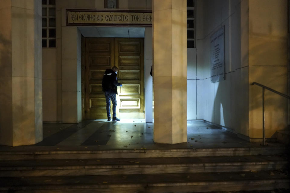 A police officer searches for clues after a priest was shot, Saturday Oct. 31, 2020, in the city of Lyon, central France. A Greek Orthodox priest was shot while he was closing his church in the French city of Lyon, and authorities locked down part of the city to hunt for the assailant. The priest, a Greek citizen, is in a local hospital with life-threatening injuries after being shot twice in the abdomen. (AP Photo/Laurent Cipriani)