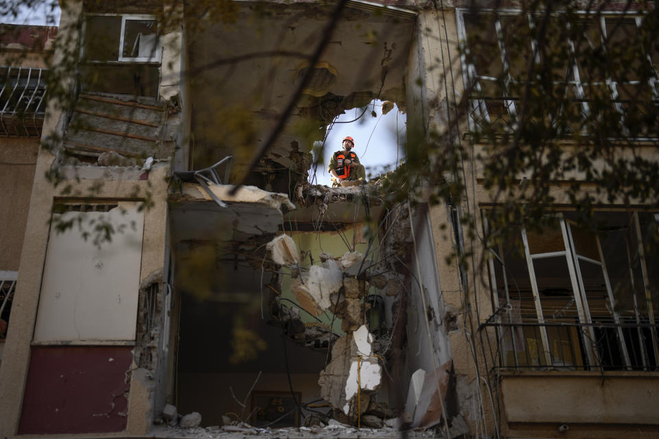 A Israeli soldier inspects a damaged residential building, a day after it was hit by a rocket fired from the Gaza Strip, in Rishon Lezion, Israel, Thursday, Oct. 26, 2023. (AP Photo/Francisco Seco)