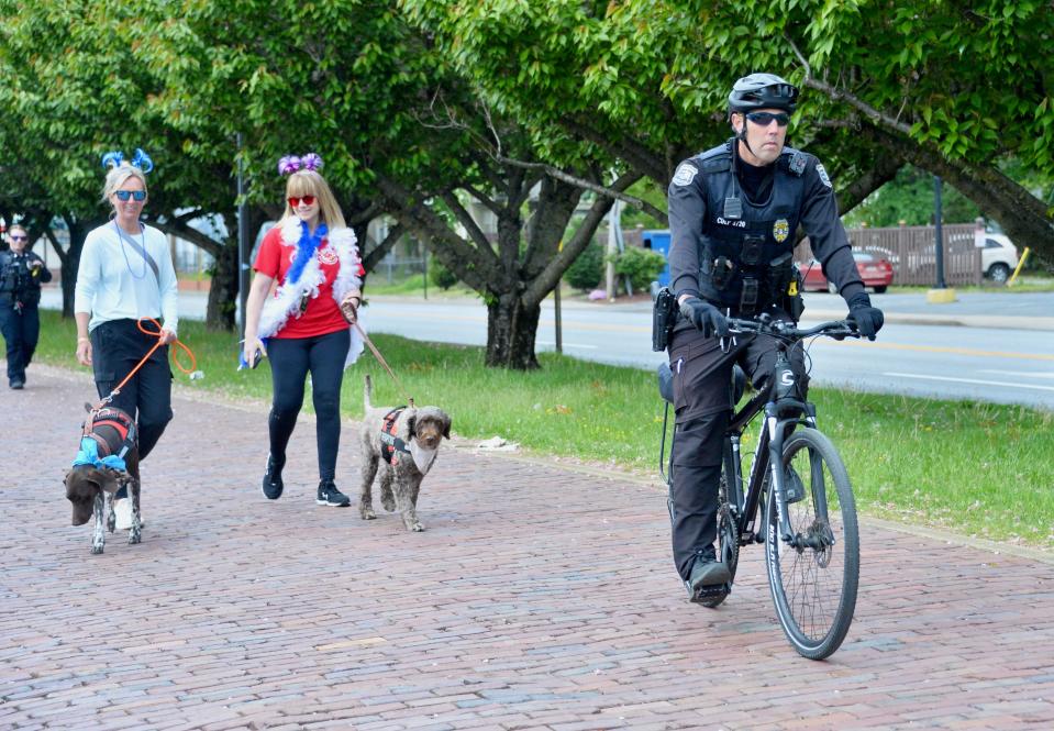Hagerstown Police Officer Tim Culp leads a group walking through the downtown Hagerstown area on Friday to recognize National Crime Victims' Rights Week. Behind Culp is Erin Hershey (left) with the Alliance of Therapy Dogs, and Jill Ritter, victim/witness coordinator for the Washington County States Attorney's Office. Hershey is walking with Greta, a German shorthaired pointer in training as a therapy dog, while Ritter is walking with therapy dog Abby, a Portuguese water dog.