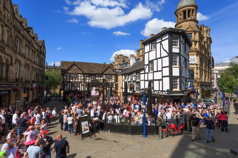Manchester, UK - July 5, 2014: Visitors to Shambles Square in central Manchester. Showing The Old Wellington pub and Sinclair's Oyster Bar. These establishments are very busy and popuar, epsecially on sunny days and they attract many stag and hen dos.