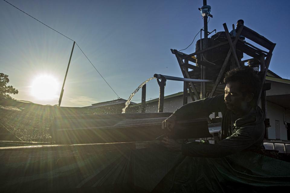 Sulaiman, a local residents, filters water extracted from a well to be sold to the companies involved in the construction of the Kalimantan Industrial Park Indonesia (KIPI), in Mangkupadi, North Kalimantan, Indonesia on Thursday, Aug. 24, 2023. Residents hope the project may bring jobs, but worry they will lose their traditional livelihoods as fishermen, farmers and increasingly, eco-tourism hosts as dust and ash smother their fields. (AP Photo/Yusuf Wahil)