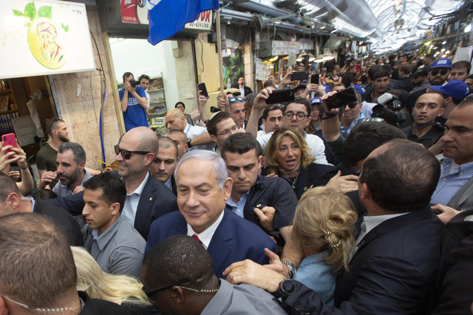 Israeli Prime Minister Benjamin Netanyahu escorted by bodyguards walks during a visit to the market on the eve of Israel's general elections in Jerusalem, Monday, April 8, 2019. (AP Photo/Sebastian Scheiner)