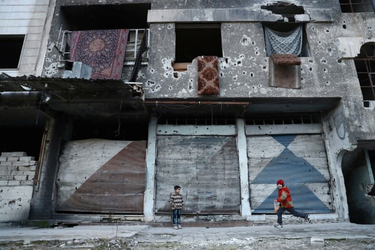 Syrian children play next to a ruined buidling in the rebel-held town of Douma on the eastern outskirts of Damascus on January 9, 2017