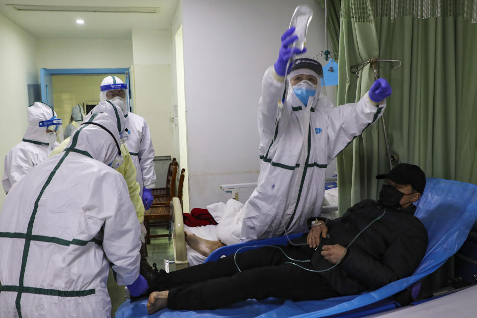 In this Thursday, Feb. 6, 2020, photo, medical workers move a man into the isolation ward for 2019-nCoV patients at a hospital in Wuhan in central China's Hubei province. The number of confirmed cases of the new virus has risen again in China on Saturday, Feb. 8, 2020, as the ruling Communist Party faced anger and recriminations from the public over the death of a doctor who was threatened by police after trying to sound the alarm about the disease over a month ago. (Chinatopix via AP)