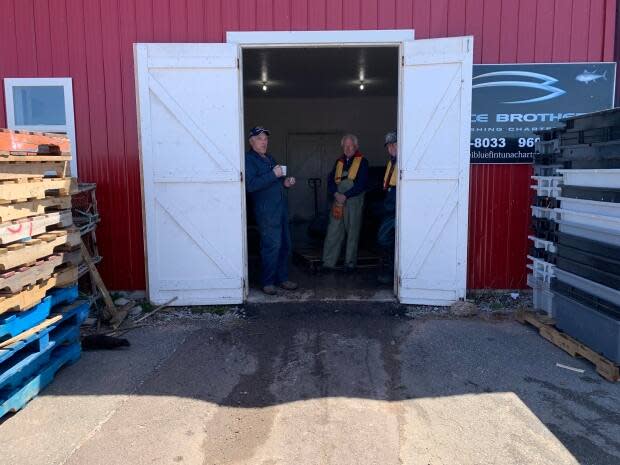 Some old-timers catch up on the talk at the North Lake wharf. The chatter is all about a dramatic drop in lobster prices on Monday. The men are entertained by the appearance of a sleek brown sea otter who streaked by, in the lower left corner. 