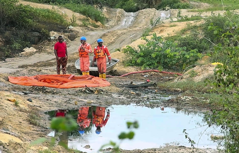 In this grab taken from video, workers stand by a container to collect oil spill waste, in Ogoniland, Nigeria, June 16, 2023. An oil spill at a Shell facility in Nigeria has contaminated farmland and a river. It's upended livelihoods in the fishing and farming communities of part of the Niger Delta, which has long endured environmental pollution caused by the oil industry. (AP Photo)