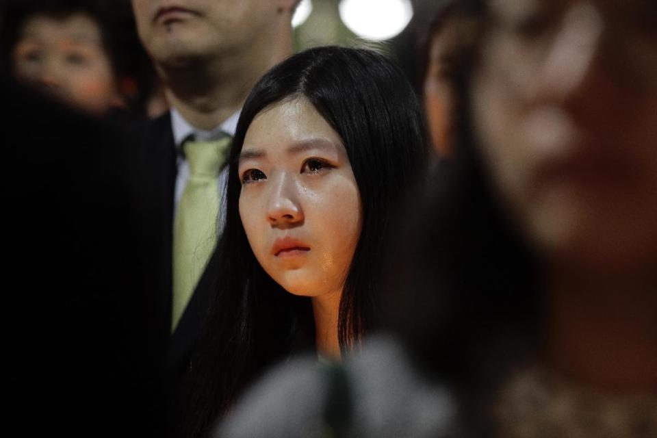 A woman joins candlelight vigil for the missing passengers of a sunken ferry at Danwon High School in Ansan, South Korea, Thursday, April 17, 2014. An immediate evacuation order was not issued for the ferry that sank off South Korea's southern coast, likely with scores of people trapped inside, because officers on the bridge were trying to stabilize the vessel after it started to list amid confusion and chaos, a crew member said Thursday. (AP Photo/Wonghae Cho)