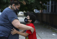 Christina Mendez leans down to hug her 7-year-old son, Elidios Kenel, after meeting with dozens of other concerned parents and students at St. Francis Xavier School in Newark, Thursday, Aug. 6, 2020. The Archdiocese of Newark announced the school's permanent closure the previous week. (AP Photo/Jessie Wardarski)