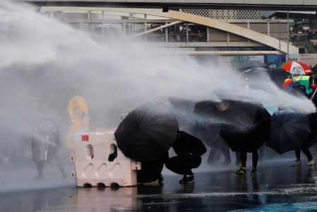 Anti-government protesters are sprayed with water cannon by the police during a demonstration near Central Government Complex in Hong Kong