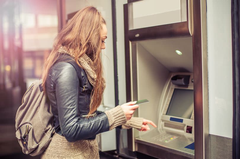 Young woman withdrawing money from credit card at ATM -Credit:guruXOOX