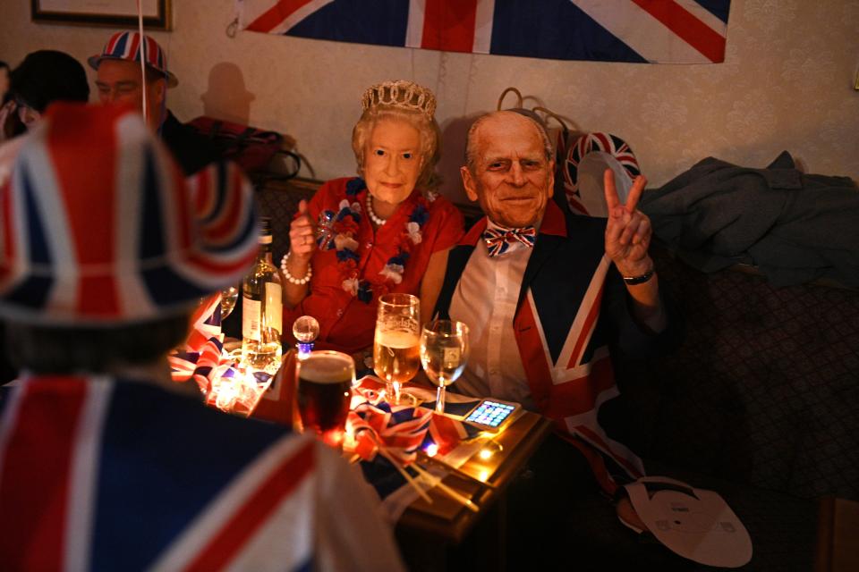 Brexit supporters wearing masks of Britain's Queen Elizabeth II and Britain's Prince Philip, Duke of Edinburgh pose for a photograph during a Brexit Celebration party