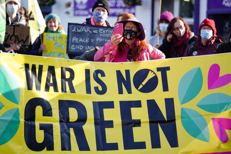 Protesters holding a sign that says "War Is Not Green"