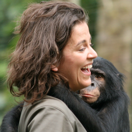 Isabel Behncke riendo con un simio en brazos.