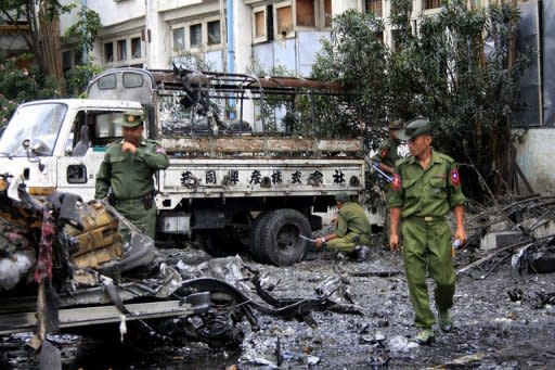 Myanmar police inspect the site of a blast which destroyed a car near the main market in the central city of Mandalay. Bomb blasts rattled three Myanmar cities including the capital, an official said, the latest in a series of explosions that authorities have mostly blamed on ethnic minority rebels