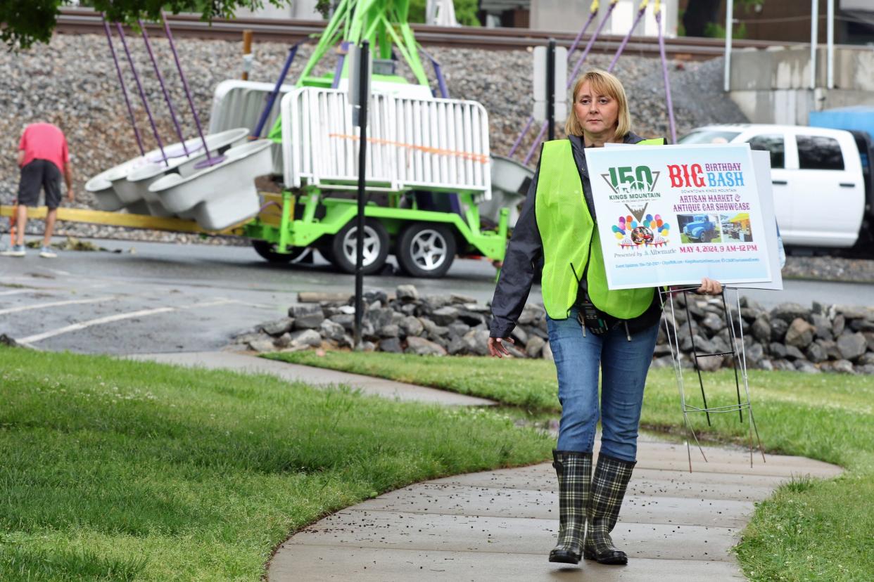 Victoria Brigman gathers up signs after rain caused the cancellation of the Kings Mountain 150th Birthday Bash Saturday, May 4, 2024.