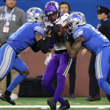 Justin Jefferson of the Vikings is tackled by two Detroit Lions.