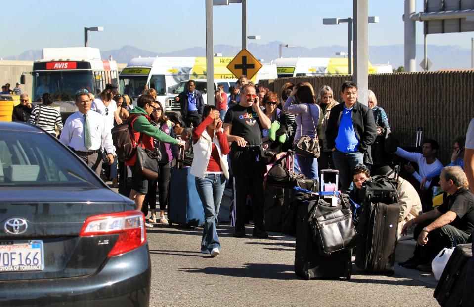 Passengers evacuate the Los Angeles International Airport on Friday Nov. 1, 2013, in Los Angeles. Shots were fired at Los Angeles International Airport, prompting authorities to evacuate a terminal and stop flights headed for the city from taking off from other airports. (AP Photo/Ringo H.W. Chiu)