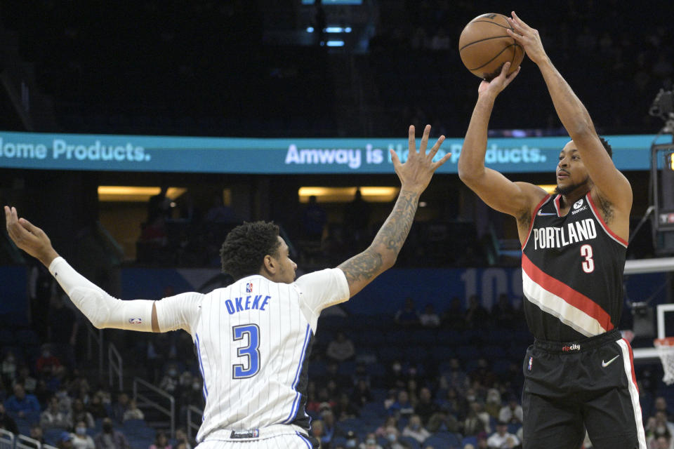 Portland Trail Blazers guard CJ McCollum, right, goes up for a three-point basket in front of Orlando Magic forward Chuma Okeke, left, during the first half of an NBA basketball game, Monday, Jan. 17, 2022, in Orlando, Fla. (AP Photo/Phelan M. Ebenhack)