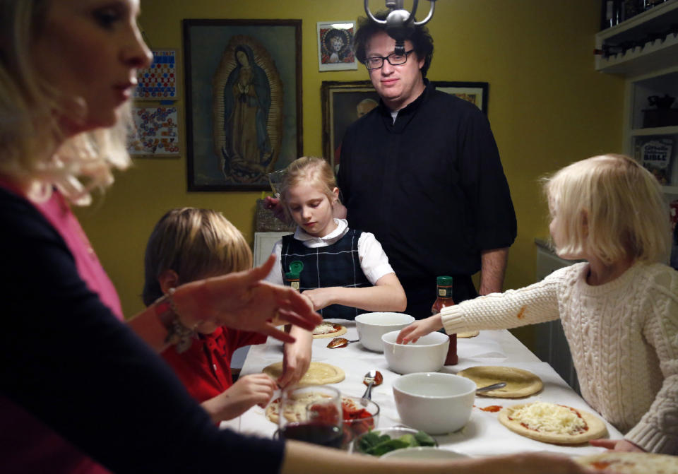 In this Feb. 7, 2020, photo, the Whitfield family, from left, wife Alli, son Peter, 8, daughter Maggie, 9, Father Joshua, and daughter Bernadette, 4, make individual pizzas at their home in north Dallas. (AP Photo/Jessie Wardarski)