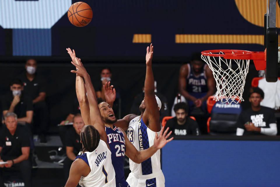 Philadelphia 76ers guard Ben Simmons (25) shoots against Indiana Pacers center Myles Turner (33) and forward T.J. Warren (1) during the fourth quarter of an NBA basketball game Saturday, Aug. 1, 2020, in Lake Buena Vista, Fla. (Kim Klement/Pool Photo via AP)
