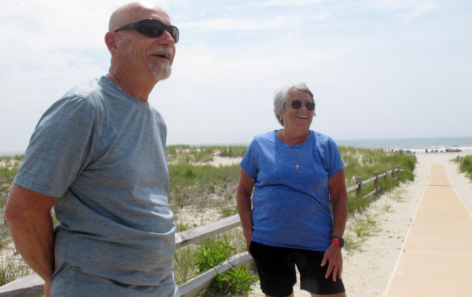 Rick Bertsch, left, and Susan Cox, right, discuss three wind energy projects that have been approved for the ocean off the coast of Ocean City, N.J., where they are standing on July 8, 2021. They oppose the projects on numerous grounds, including visual pollution, and worries about added costs and unknown impacts on the ocean and the environment. (AP Photo/Wayne Parry)