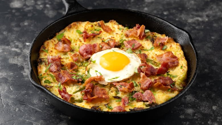 Fried potatoes in cast iron pan topped with egg 